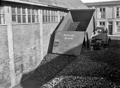 803478 Afbeelding van een vrachtauto tijdens het lossen van een kolenlaadkist van de N.S. met steenkool te Dordrecht.